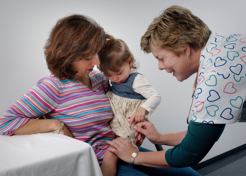 A mother and nurse smiling at a toddler during a check-up