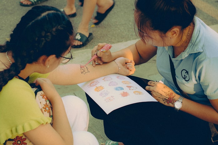 A child having a drawing added to their arm by a friend