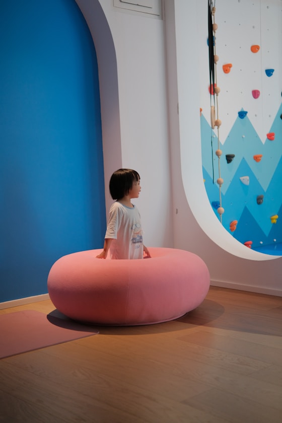 A child standing inside a soft pink sensory seat in a play room