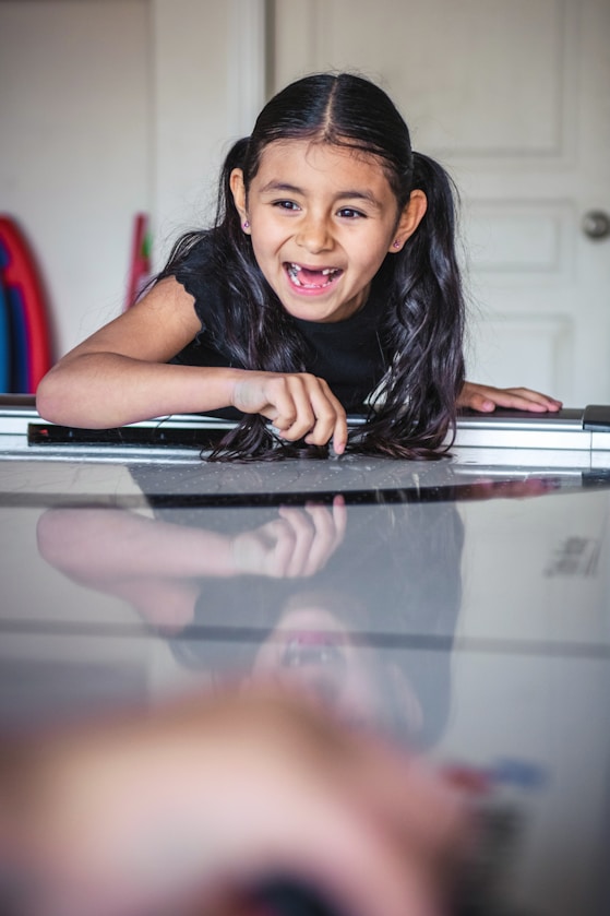 A girl leaning on a reflective table, smiling