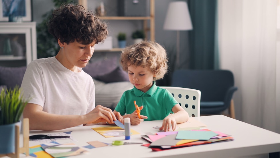A mother and son doing crafts with coloured paper