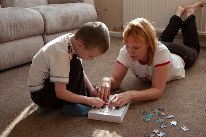 A mother and son completing a jigsaw puzzle on the floor