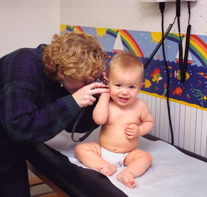 A nurse checking a baby's ear with an otoscope
