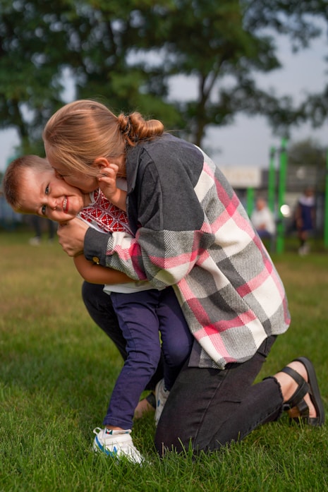 A mother and child hugging playfully outdoors