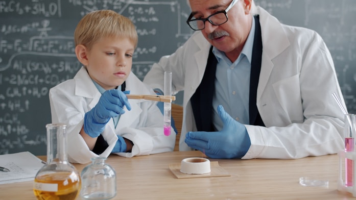 A boy and an older scientist examining a test tube together