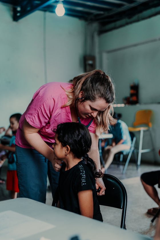 A woman helping a girl at a table