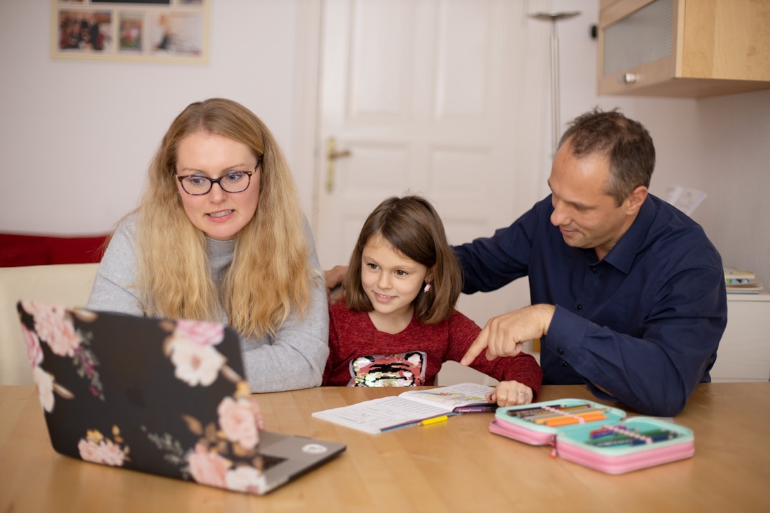 A mother and father helping their daughter with schoolwork