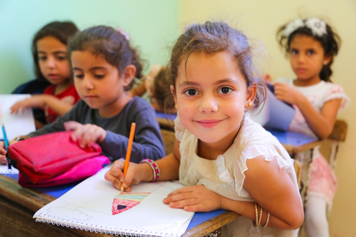 A girl smiling while writing at a classroom desk