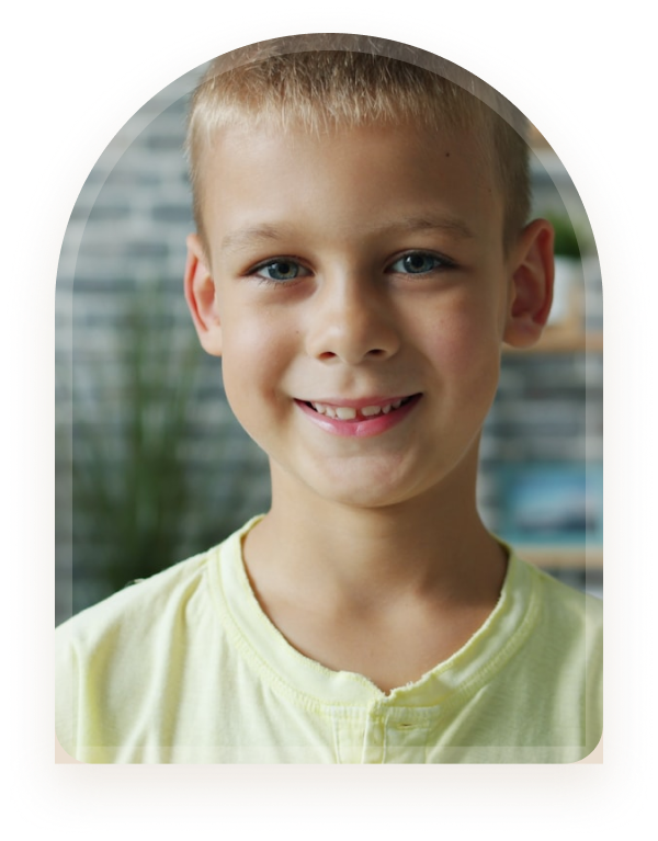 A smiling young boy in front of a brick wall
