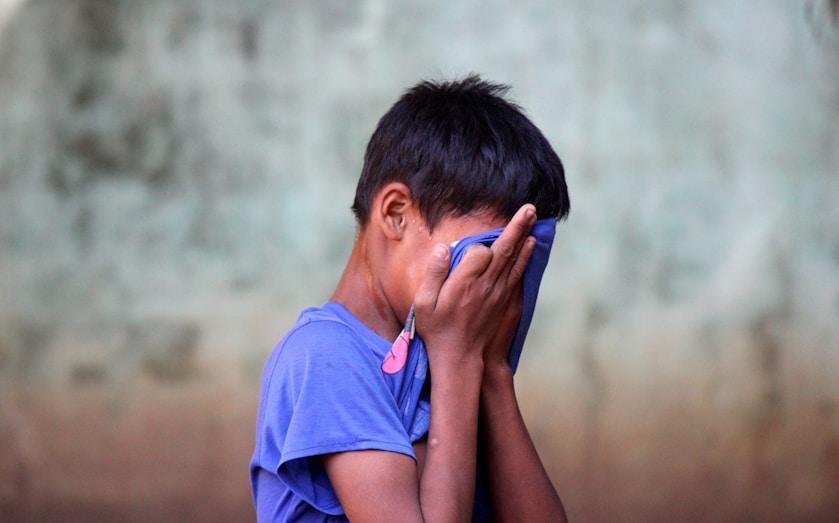 A boy holding a cloth to his face