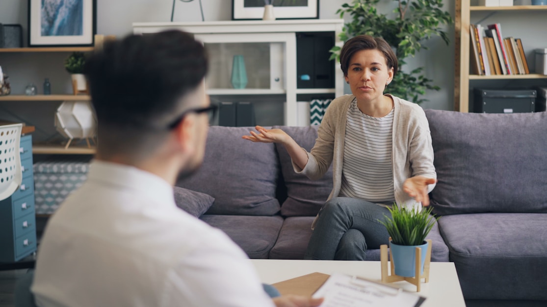 A woman gesturing while talking with a man taking notes