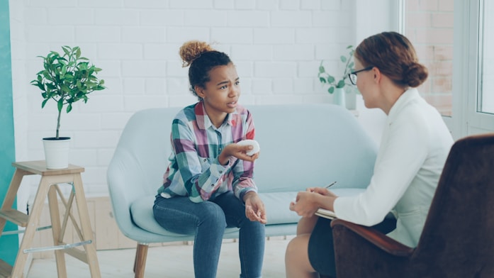 A girl talking with a therapist in a bright room
