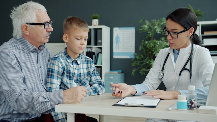 A grandfather and grandson meeting with a doctor at her desk