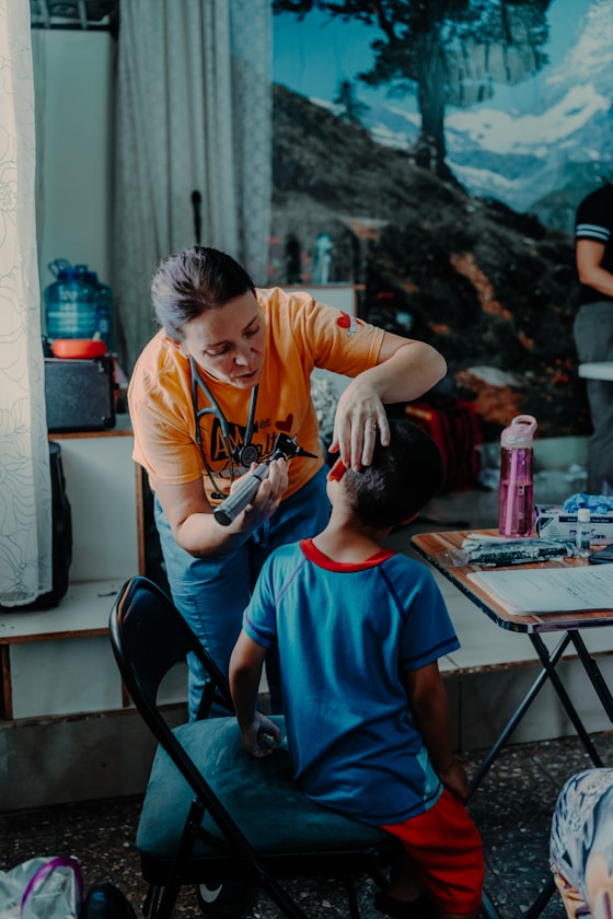 A clinician checking a boy's ear with an otoscope