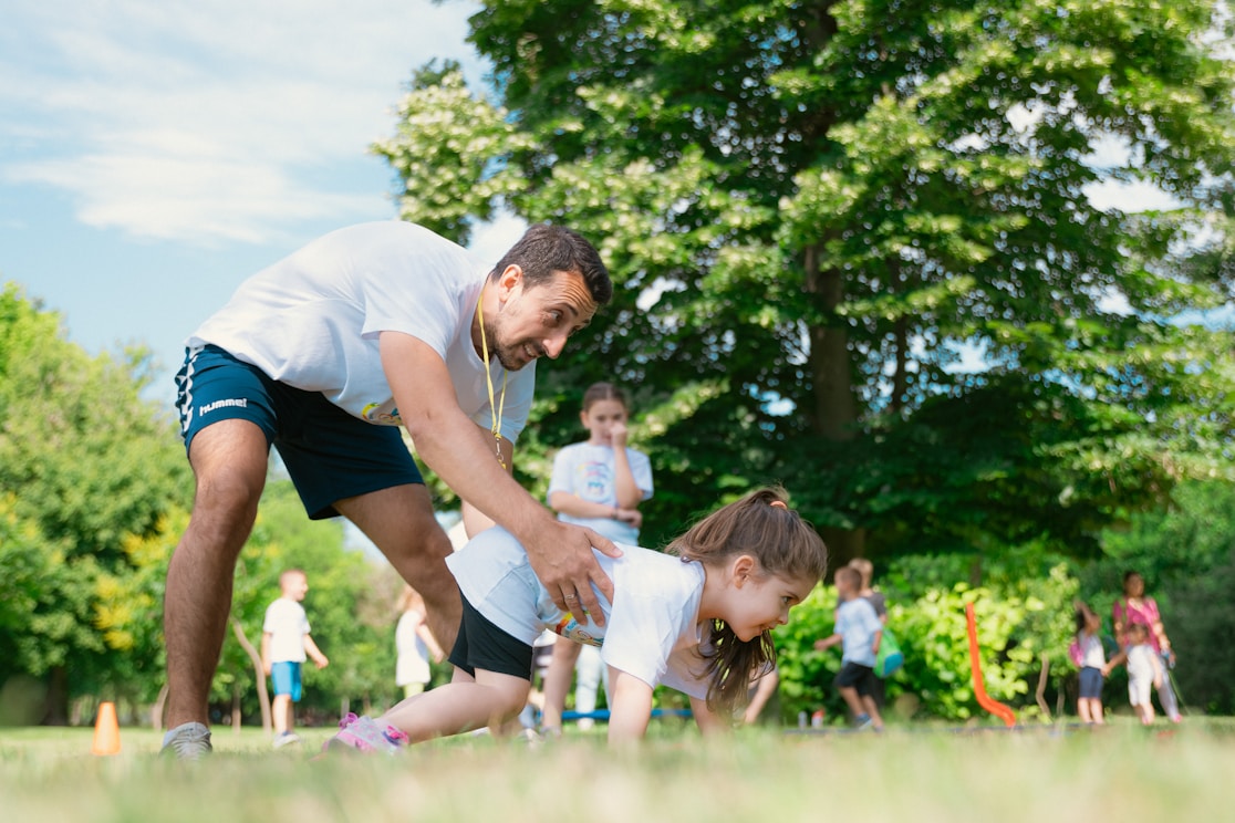A man guiding a girl through an outdoor obstacle activity
