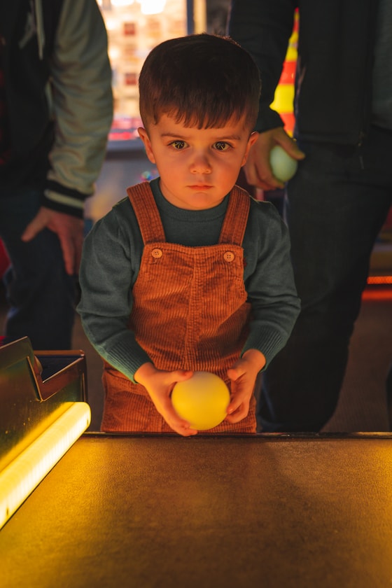 A boy holding a ball at an arcade game