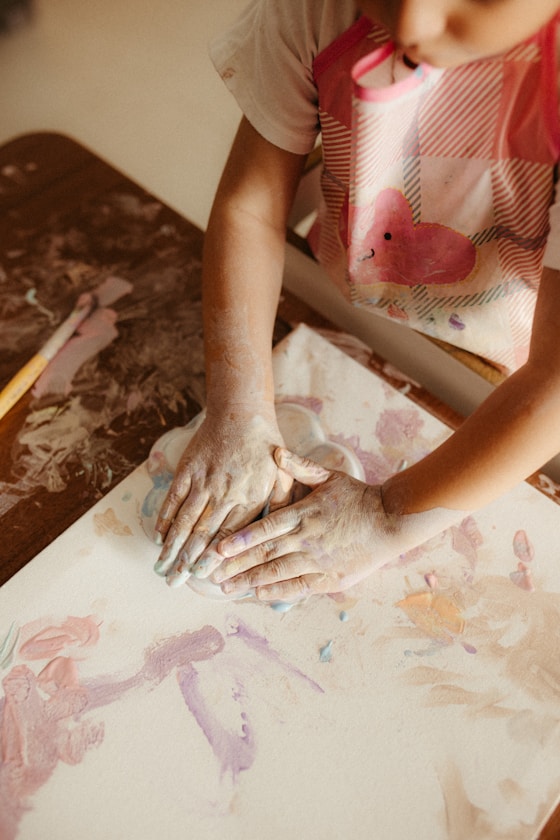 A child pressing their hands into a painted canvas