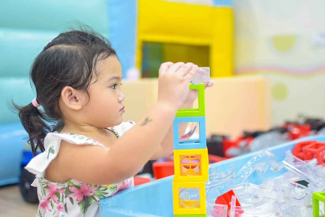 A toddler stacking colourful toy blocks
