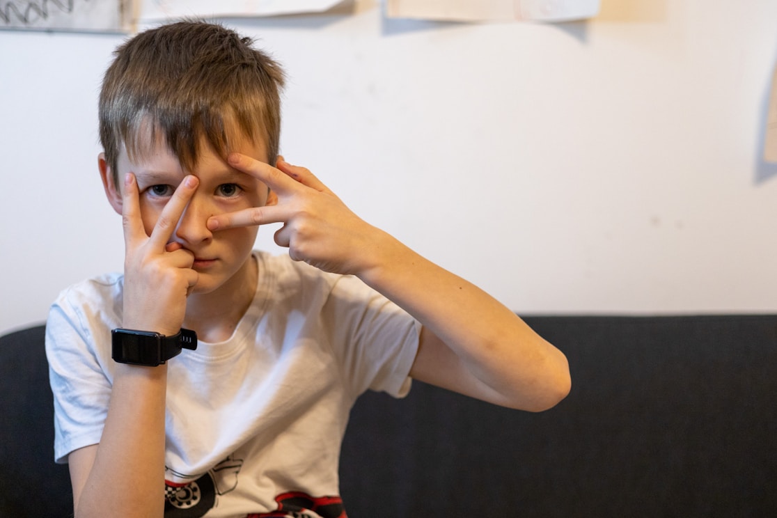 A boy making a hand gesture in front of his eyes