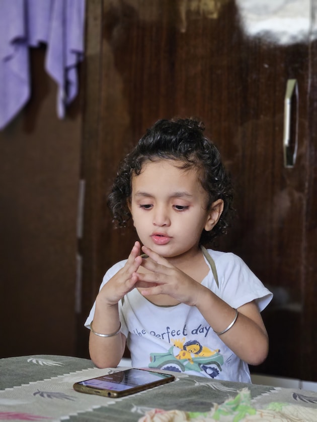 A girl with her hands near her face at a table