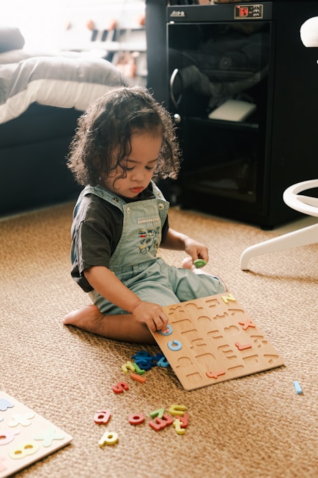 A toddler sitting on the floor playing with a shape puzzle