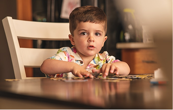A boy playing with a puzzle at a wooden table