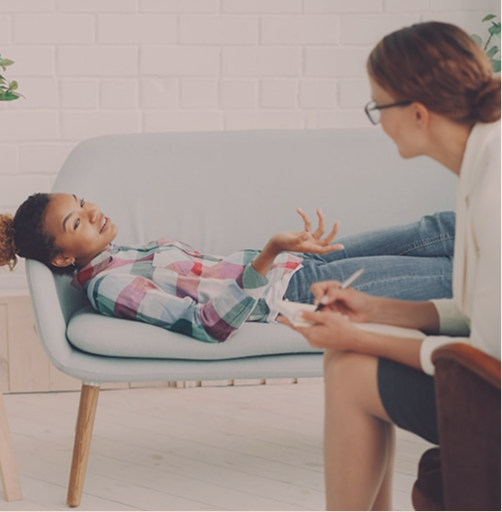 A teenager talking with a therapist in a calm therapy room at Hiba by Anthalora