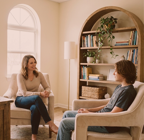 A psychologist talking with a teenager in a bright therapy room at Hiba by Anthalora