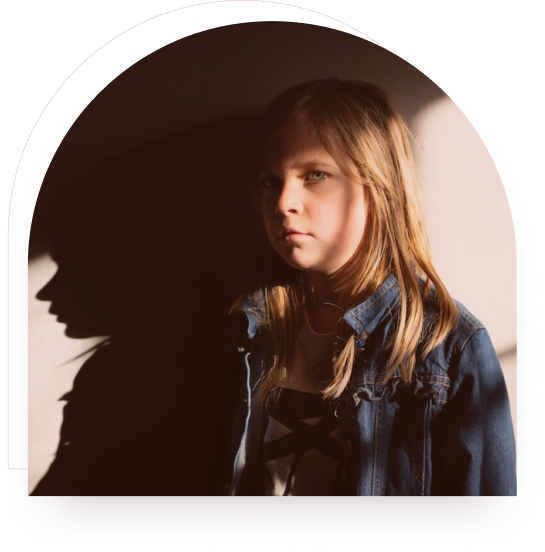 A girl standing thoughtfully with her shadow cast on the wall