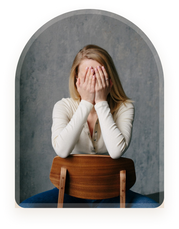 A young woman sitting with her arms resting on a wooden chair