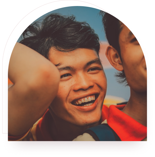A boy laughing with his arms raised outdoors