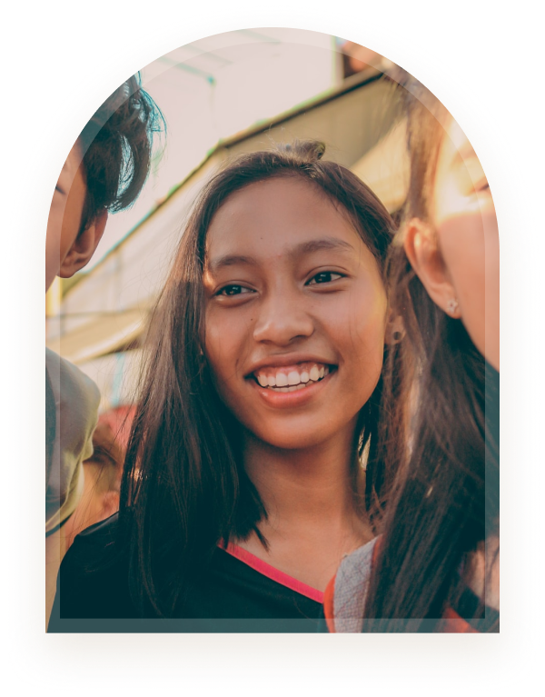 A girl smiling brightly outdoors with friends