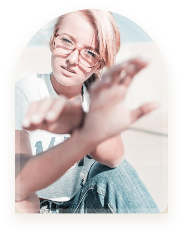 A young woman wearing glasses reaching her hand toward the camera