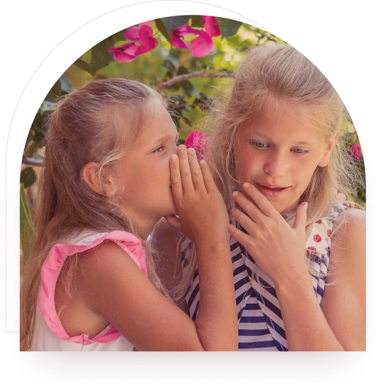 Two girls whispering and sharing a secret outdoors