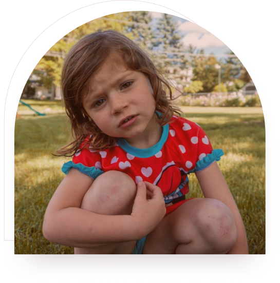 A girl crouching outdoors hugging her knees