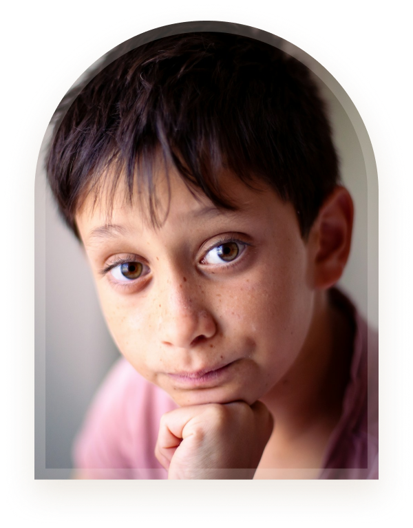 A boy resting his chin on his hand looking thoughtful