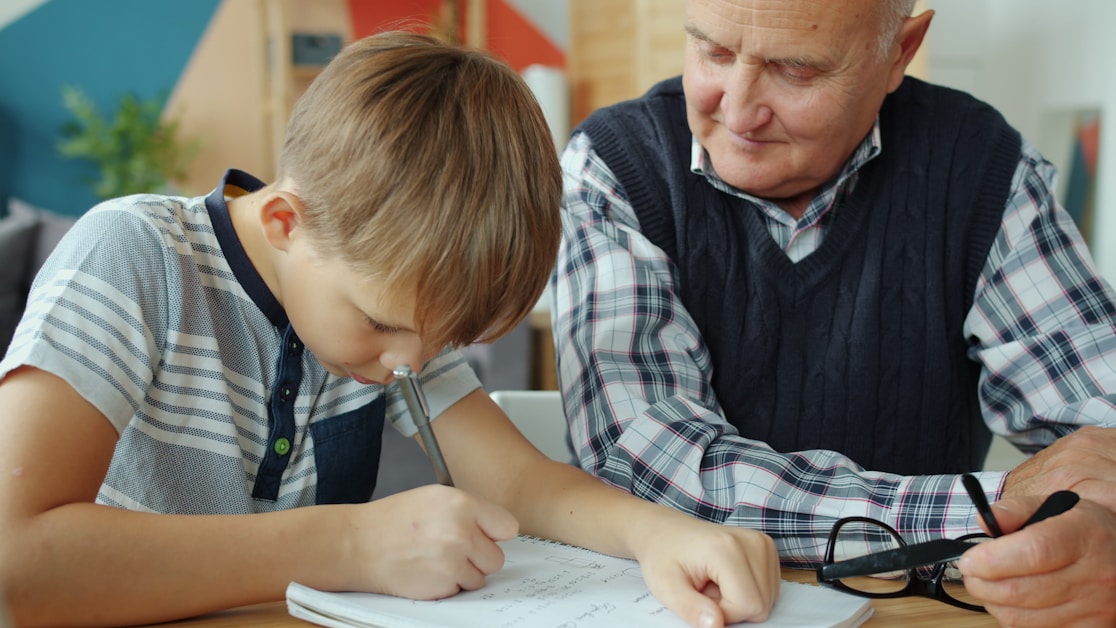 A grandfather helping a boy with his schoolwork